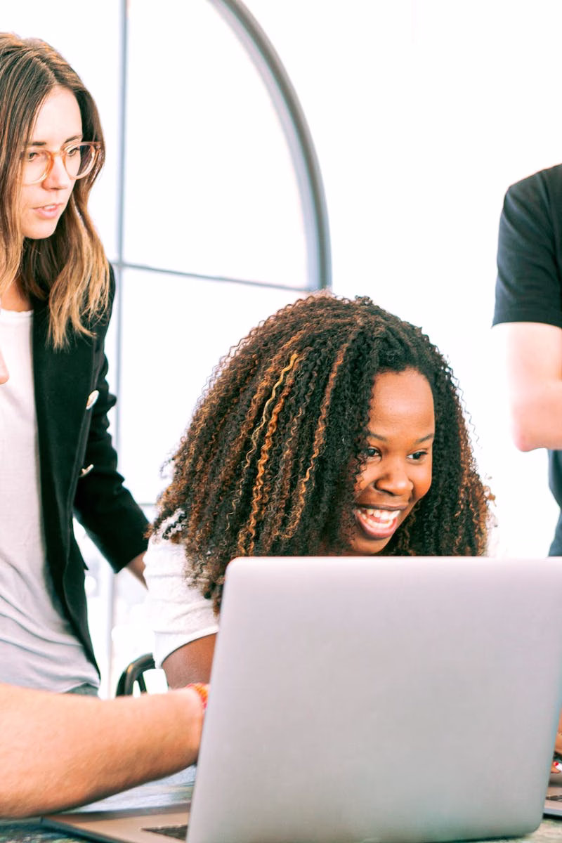 A diverse group of young professionals collaborating enthusiastically in a bright, modern workspace.
