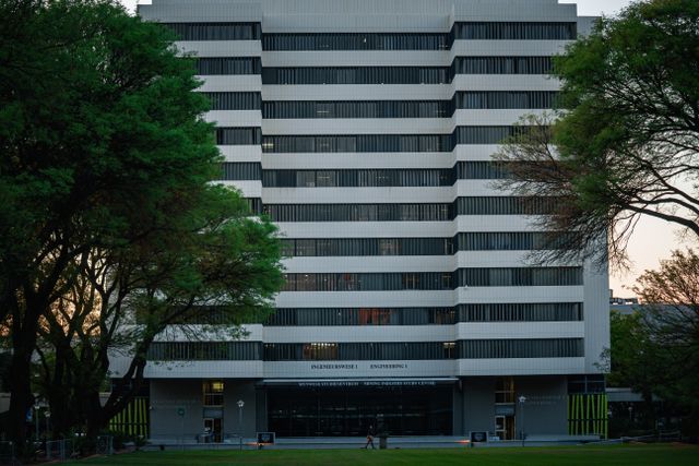 Modern university building exterior in Pretoria surrounded by trees.